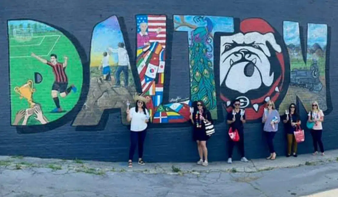 Soni and Snipes Orthodontics team in front of Dalton wall art